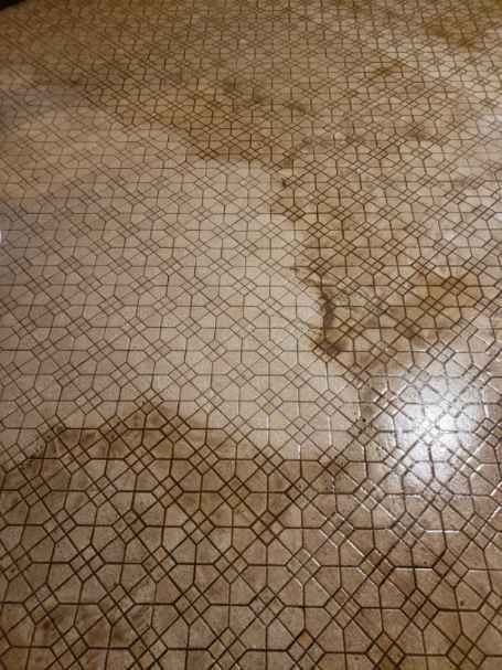 Tan patterned floor with water damage.