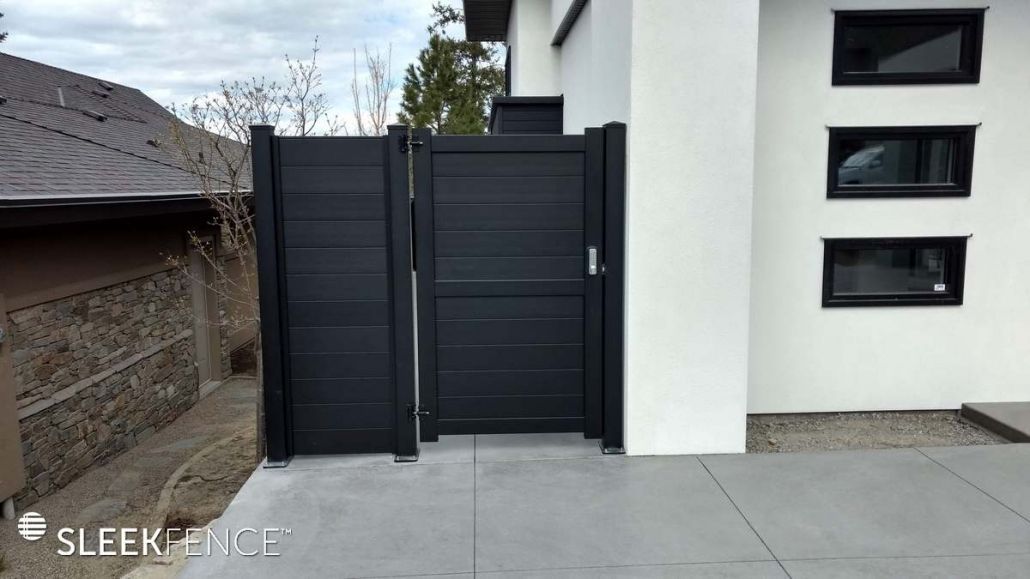A black gate is sitting in front of a white building.