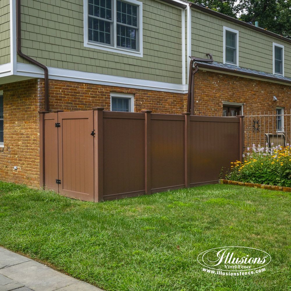 A brown fence is in front of a brick house.