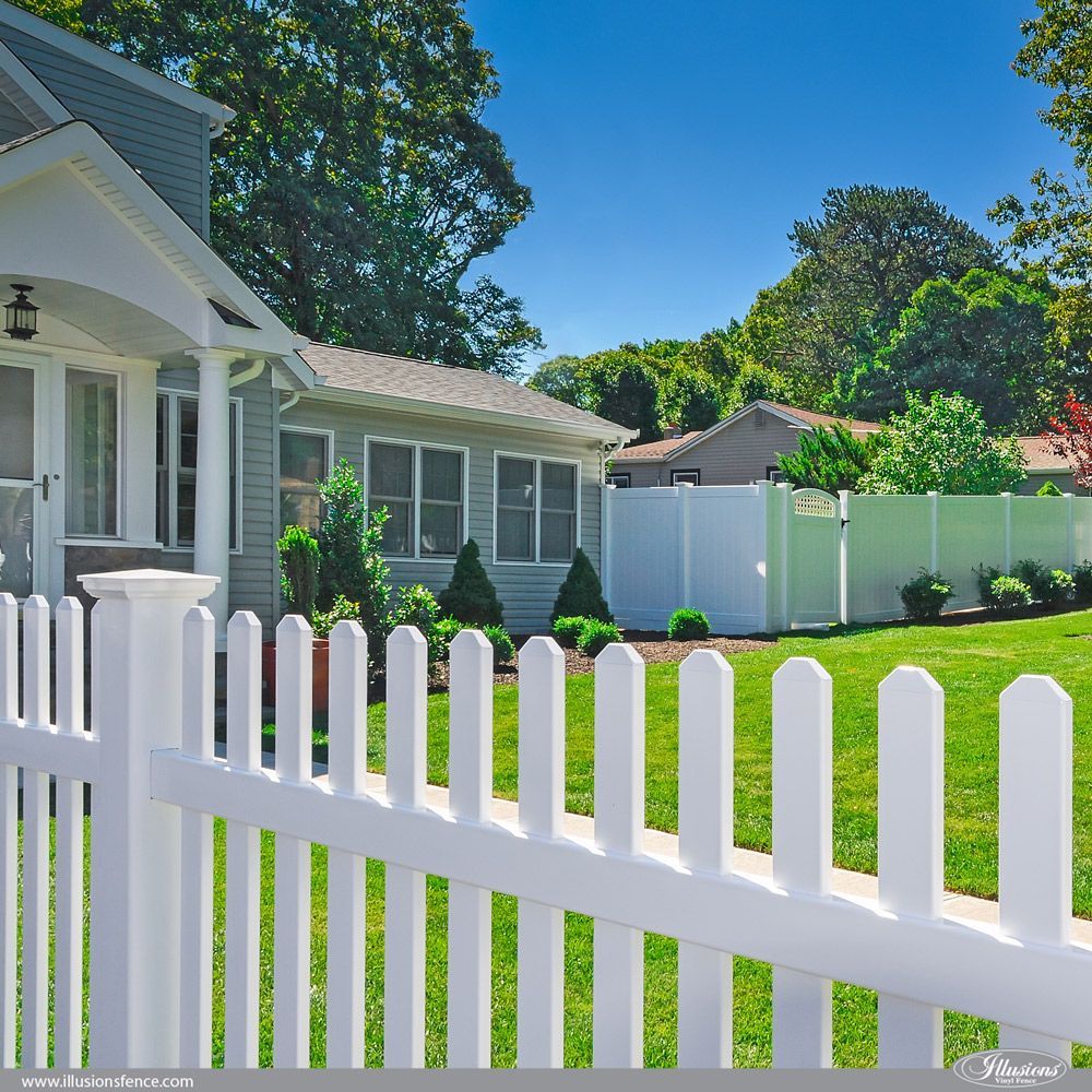A white picket fence is in front of a house