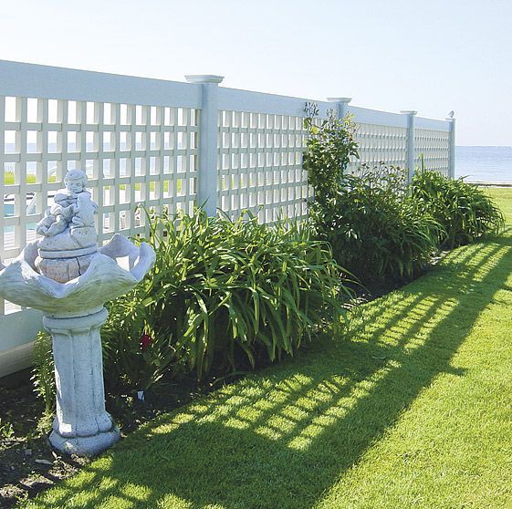 A white lattice fence surrounds a lush green lawn
