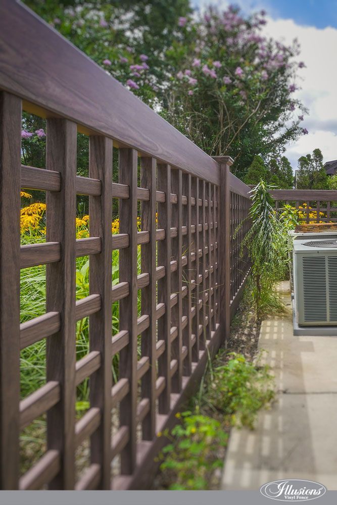 A wooden fence is surrounded by flowers and trees in a garden.
