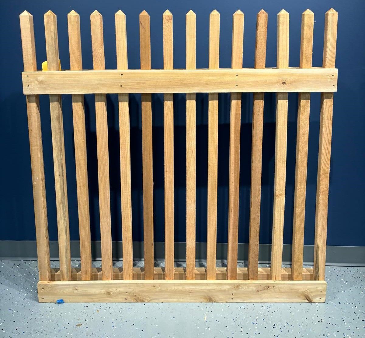 A wooden fence with a blue wall in the background