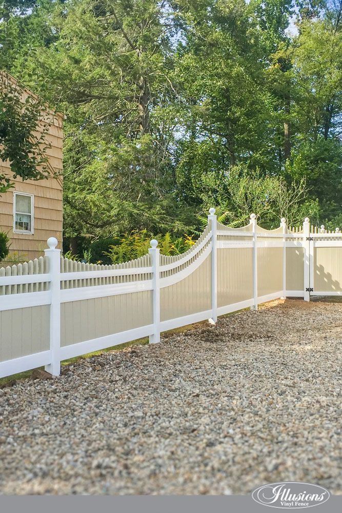 A white fence is surrounded by gravel in front of a house.