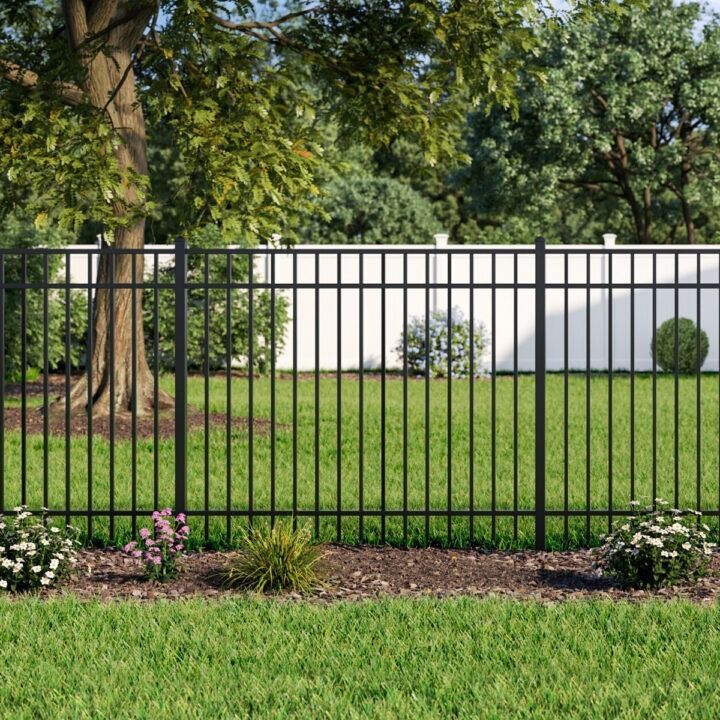 A black metal fence surrounds a lush green yard.