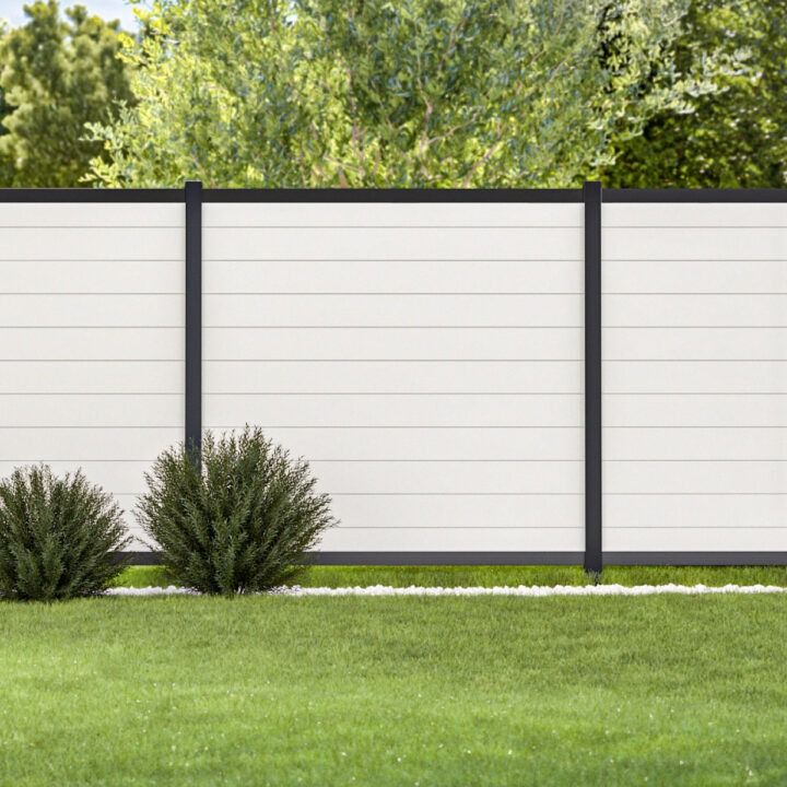 A white fence with a black frame is sitting on top of a lush green lawn.