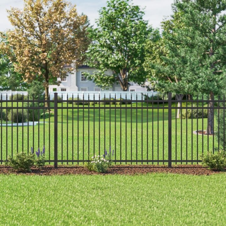 A black metal fence surrounds a lush green yard.