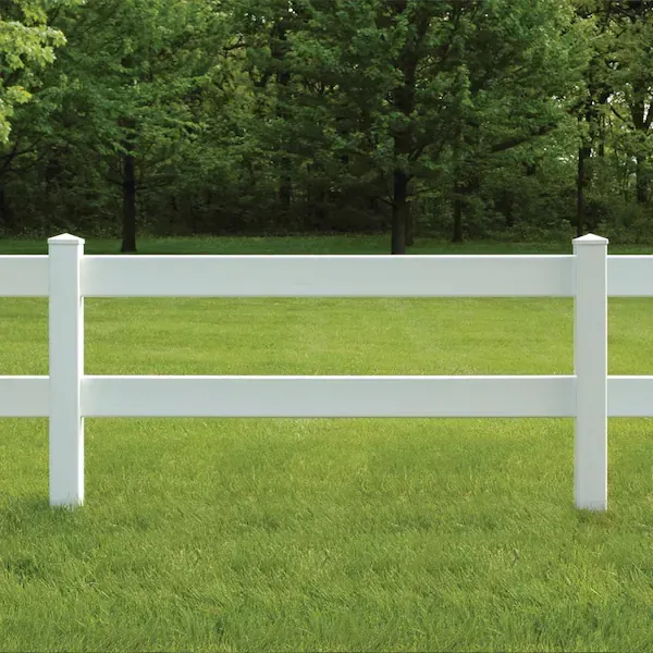 A white fence is in the middle of a lush green field.