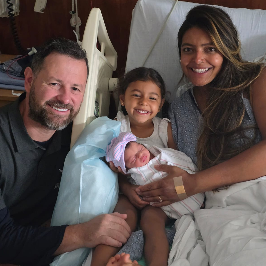 A man and woman are holding a baby in a hospital bed