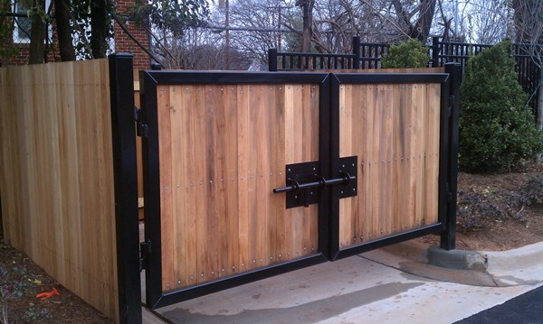 A wooden gate with a black frame is sitting next to a wooden fence.