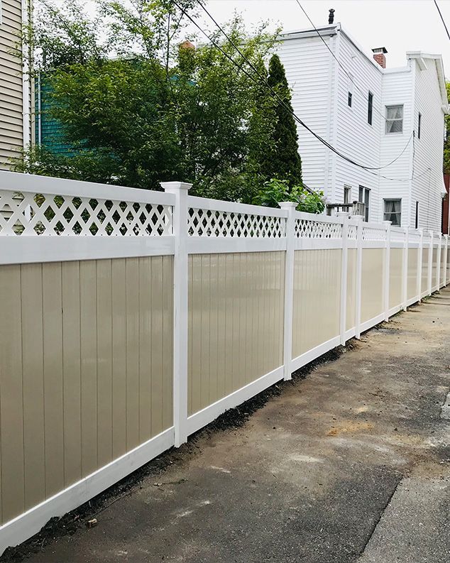 A white and tan fence along a sidewalk next to a house.