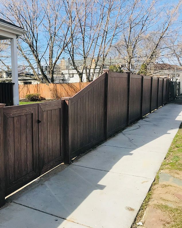 A wooden fence along a sidewalk next to a house.
