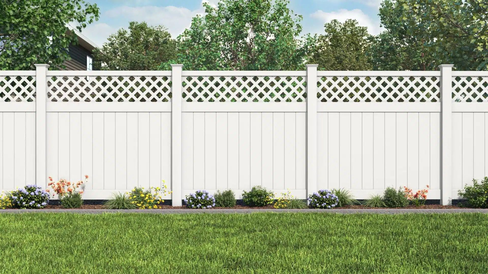 A white fence with a lattice design is in the middle of a lush green yard.