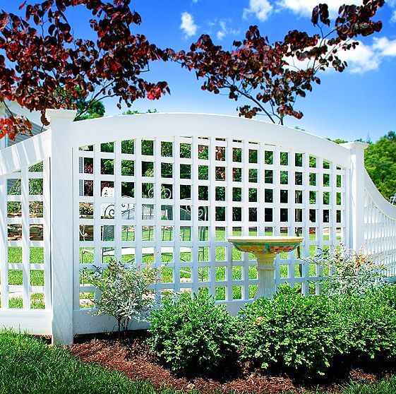 A white lattice fence with a bird bath in front of it