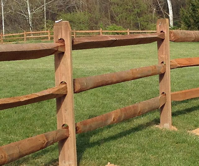 A wooden fence surrounds a lush green field