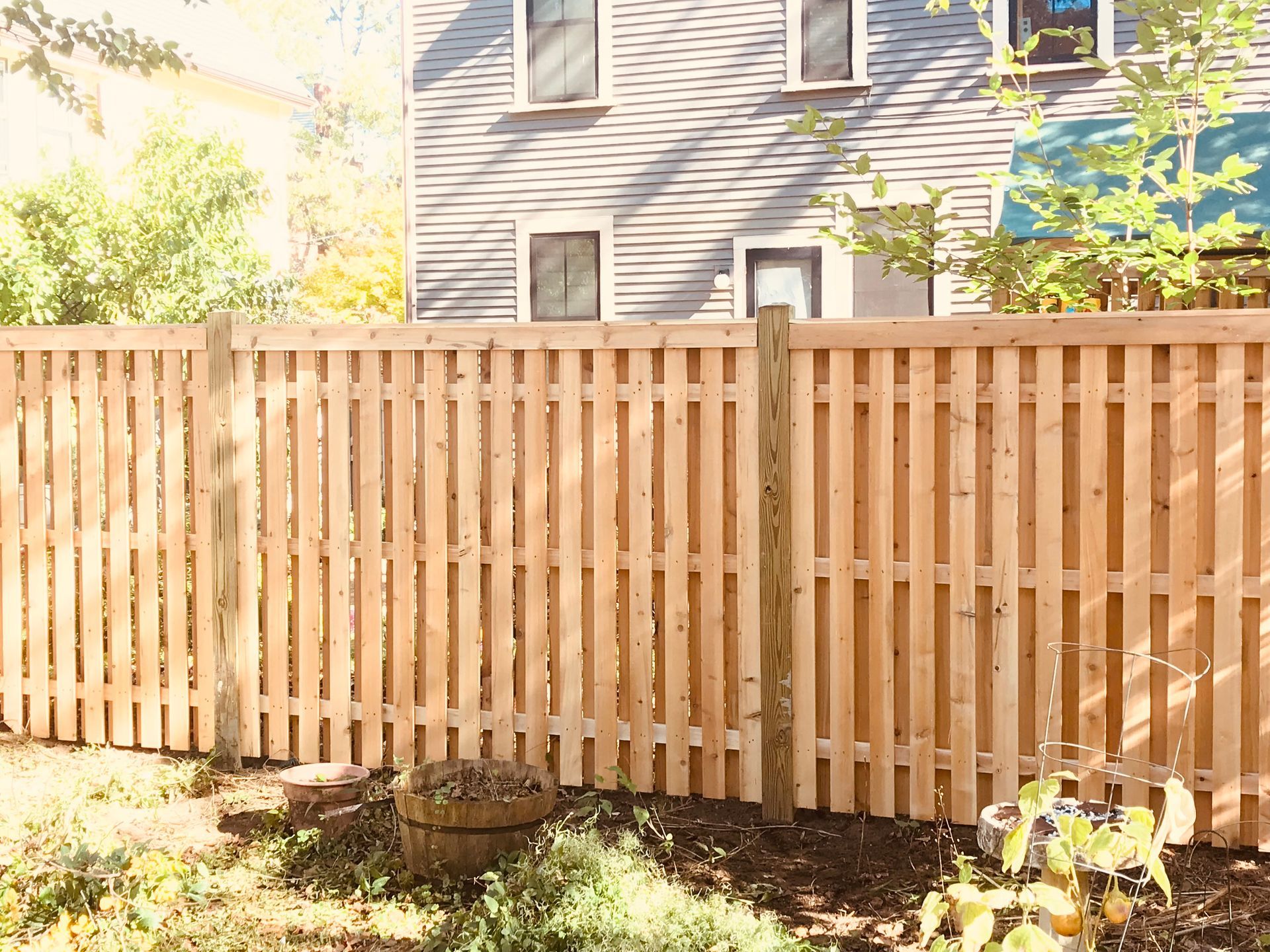A wooden fence is in the backyard of a house.