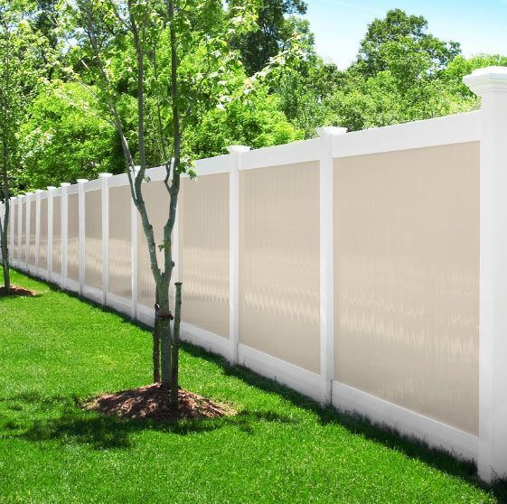 A white fence surrounds a lush green lawn with trees in the background.