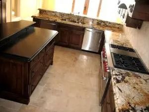 Kitchen with dark wood cabinetry, granite countertops, stainless steel appliances, and light-colored floors.