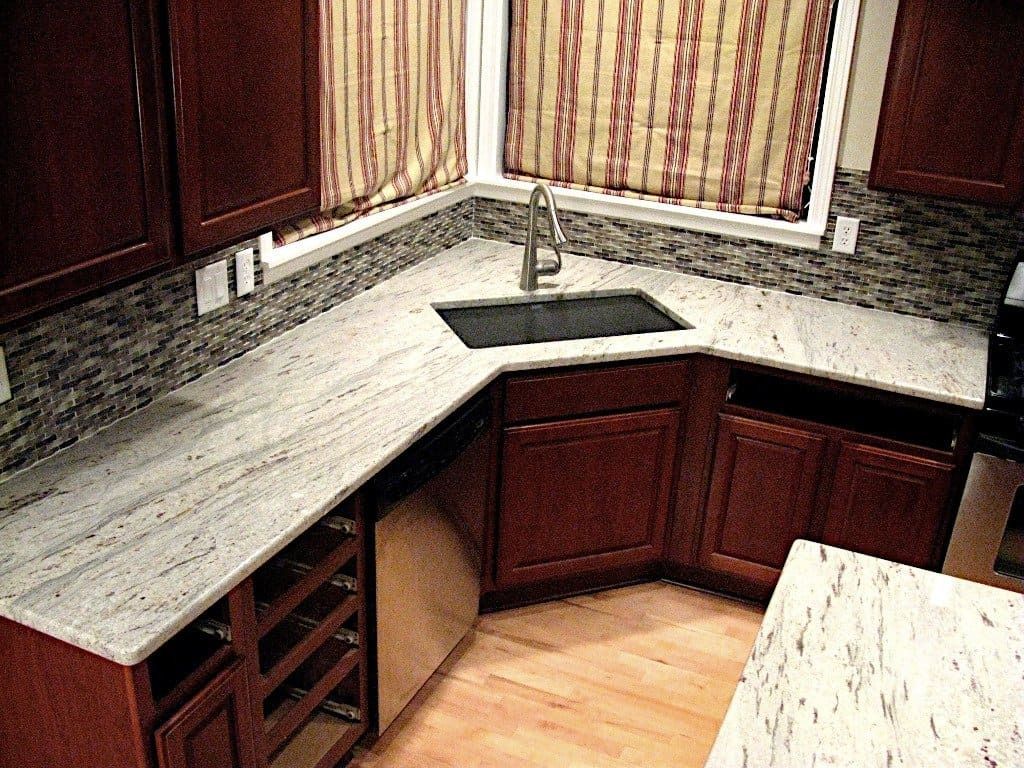 Kitchen corner with granite countertops, brown cabinets, stainless steel sink and dishwasher.