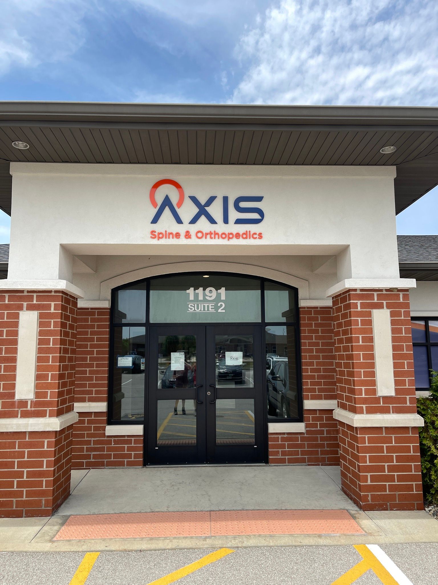 Exterior of Axis Spine & Orthopedics building with brick accents and a blue sky.
