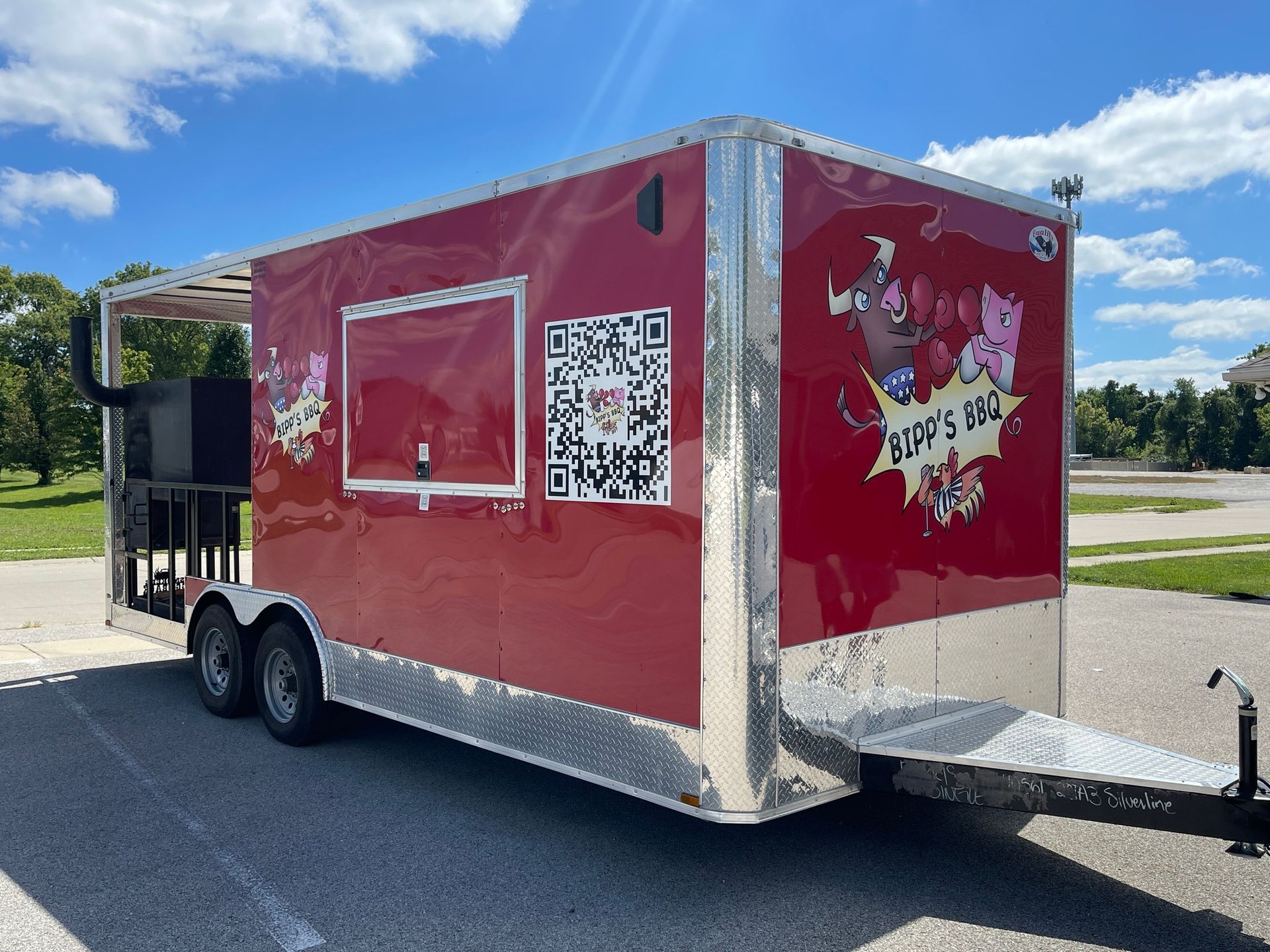 Red food trailer with pig logo, window, QR code, and awning, parked outdoors.