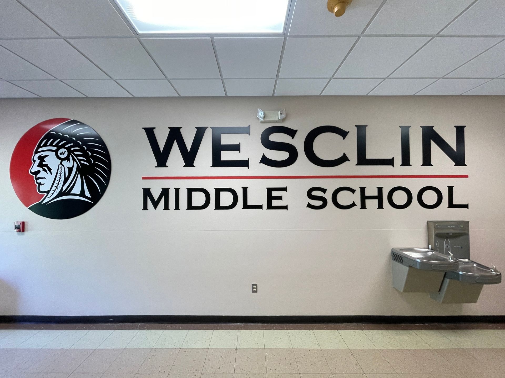 Wesclin Middle School logo on a wall with a water fountain.