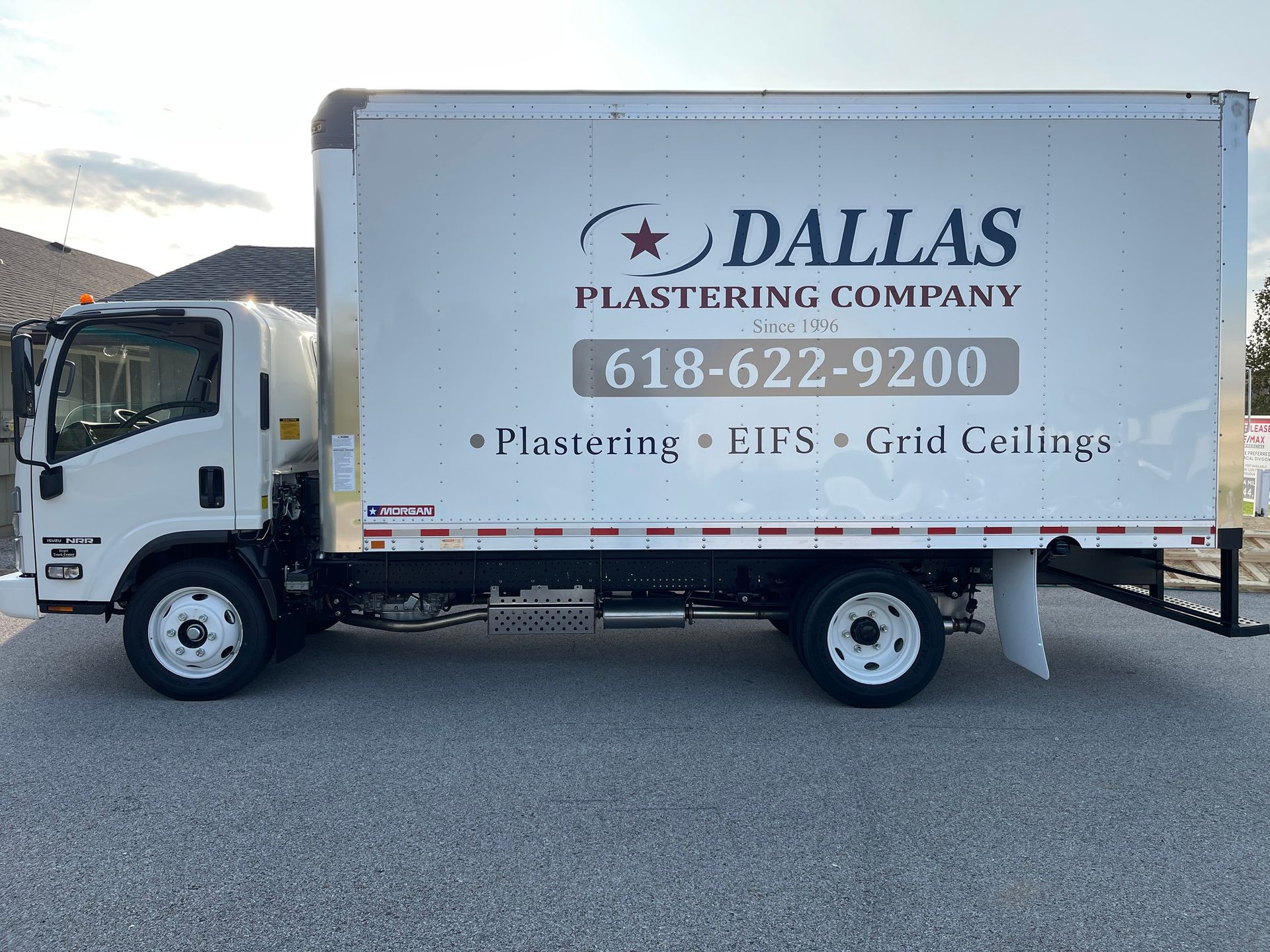 White box truck of Dallas Plastering Company with logo and phone number, parked on pavement.