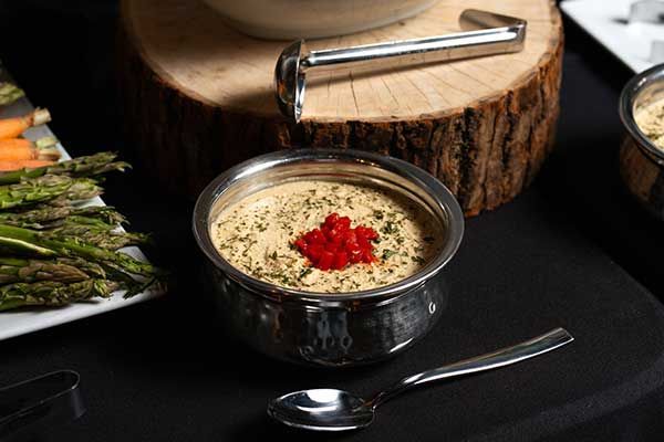 A bowl of soup with a spoon and asparagus on a table.