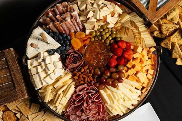 A large platter filled with cheese , meat , nuts , and fruit.