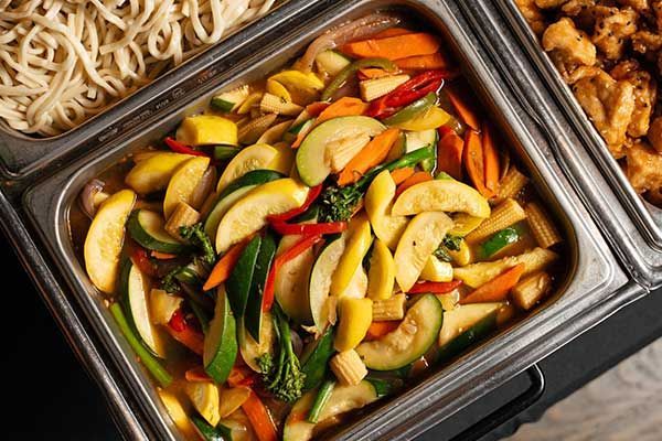 A buffet tray filled with vegetables and noodles.