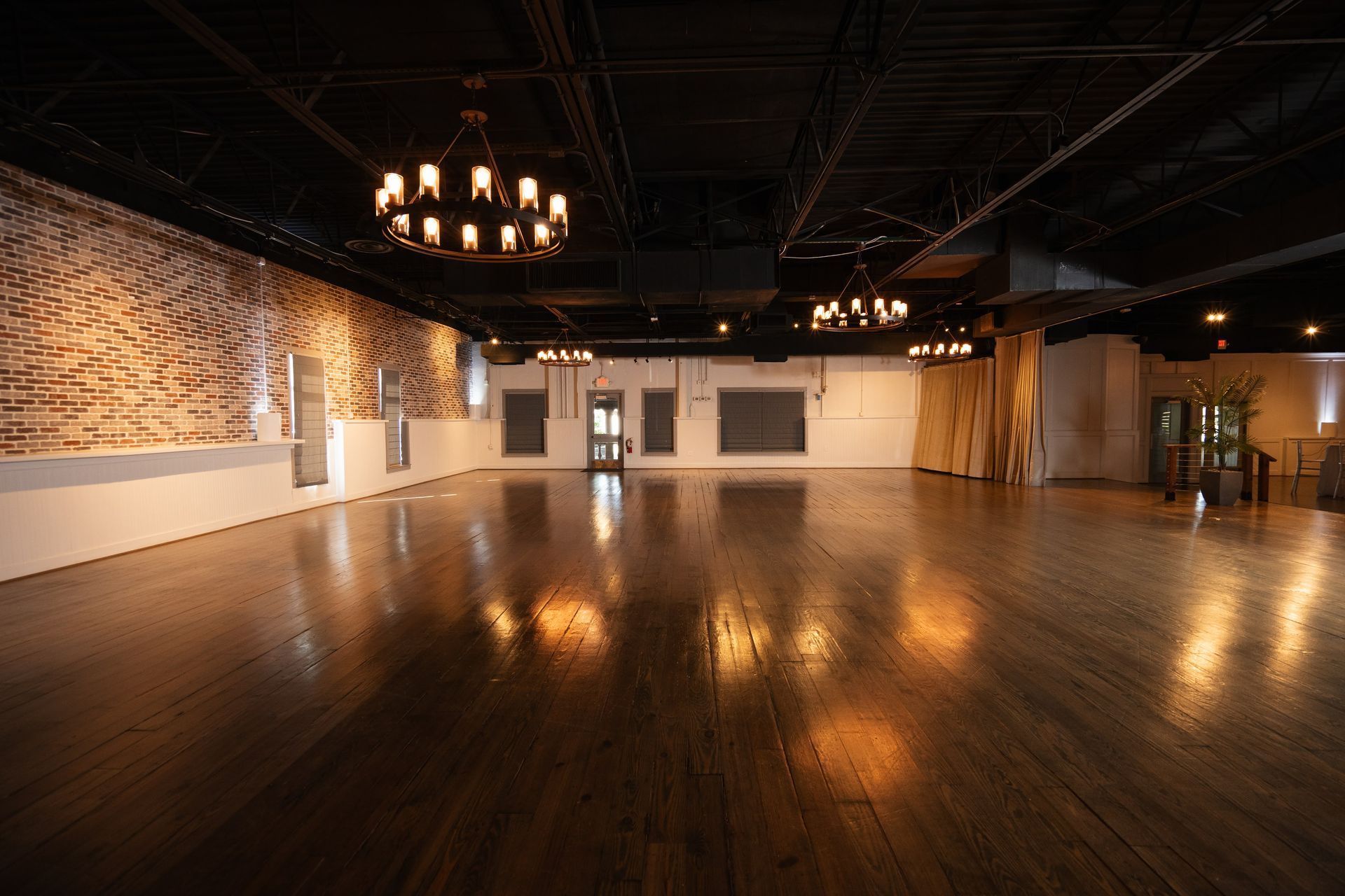 A large empty room with a wooden floor and a chandelier.