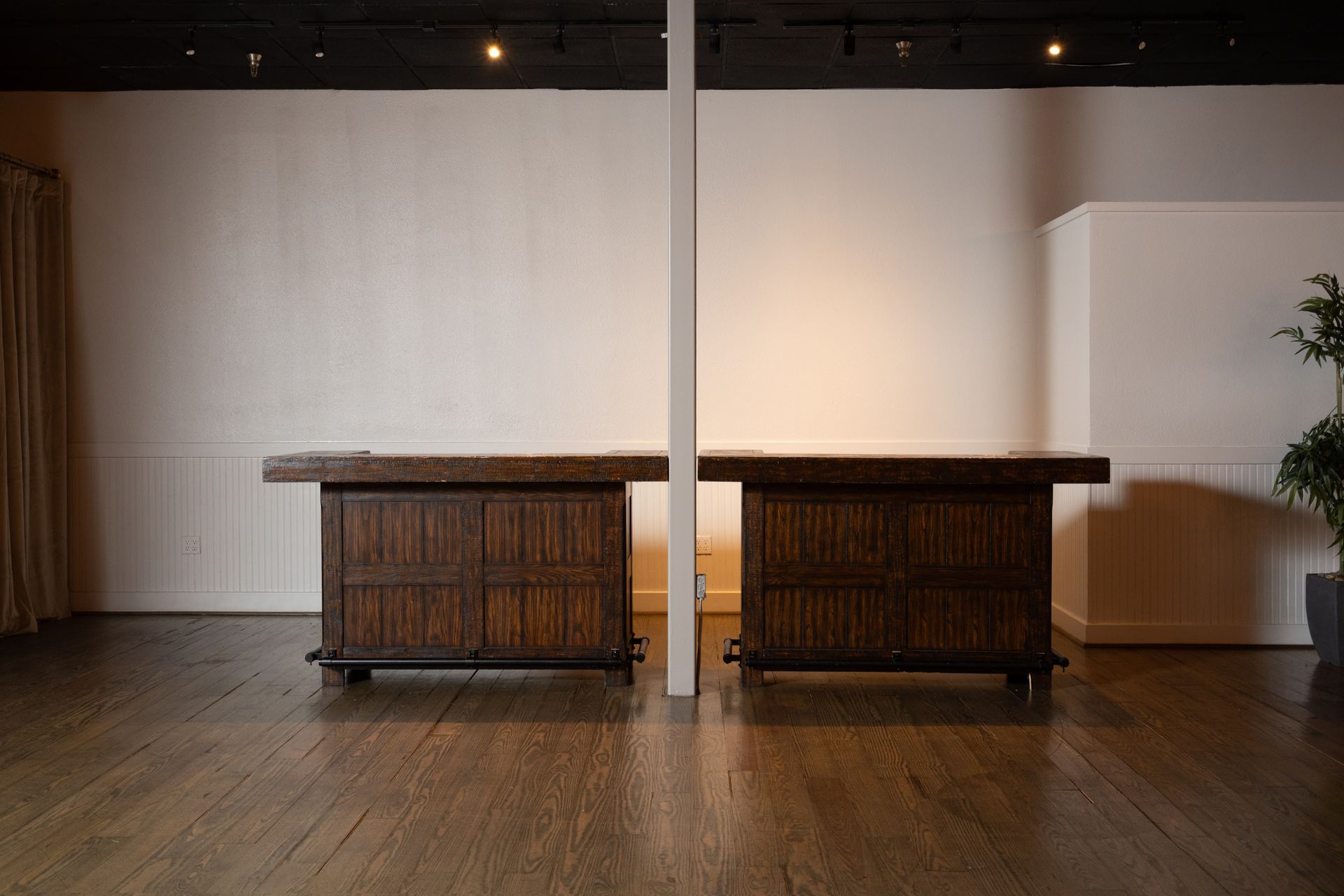 Two wooden tables are sitting next to each other in an empty room.