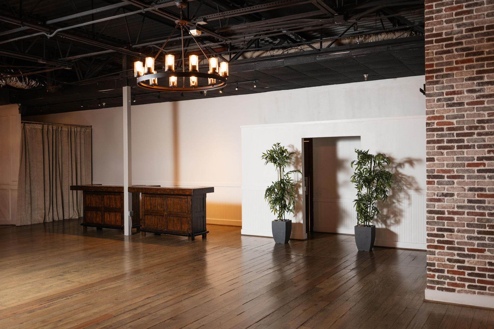 A large empty room with a wooden floor and a brick wall.