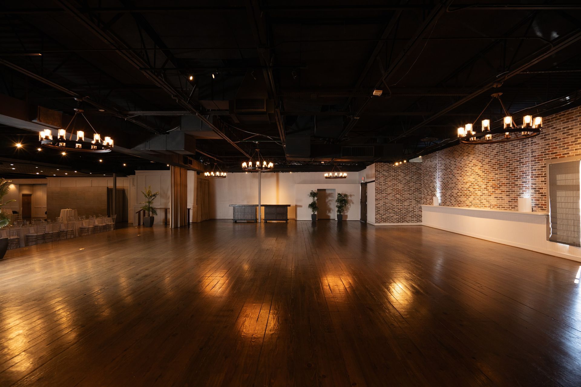 A large empty room with a wooden floor and a brick wall.