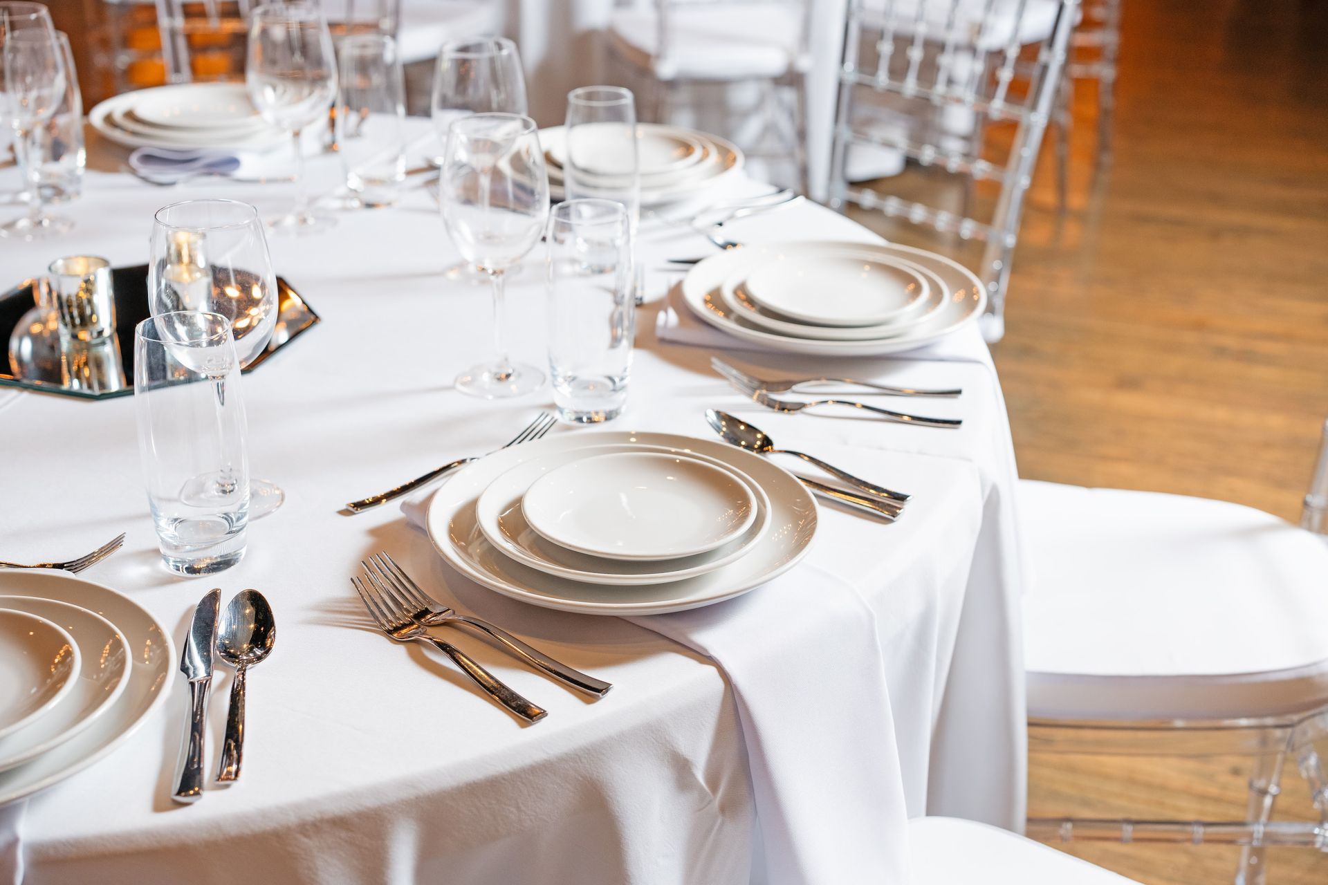 A table set for a wedding reception with plates , silverware , glasses and candles.
