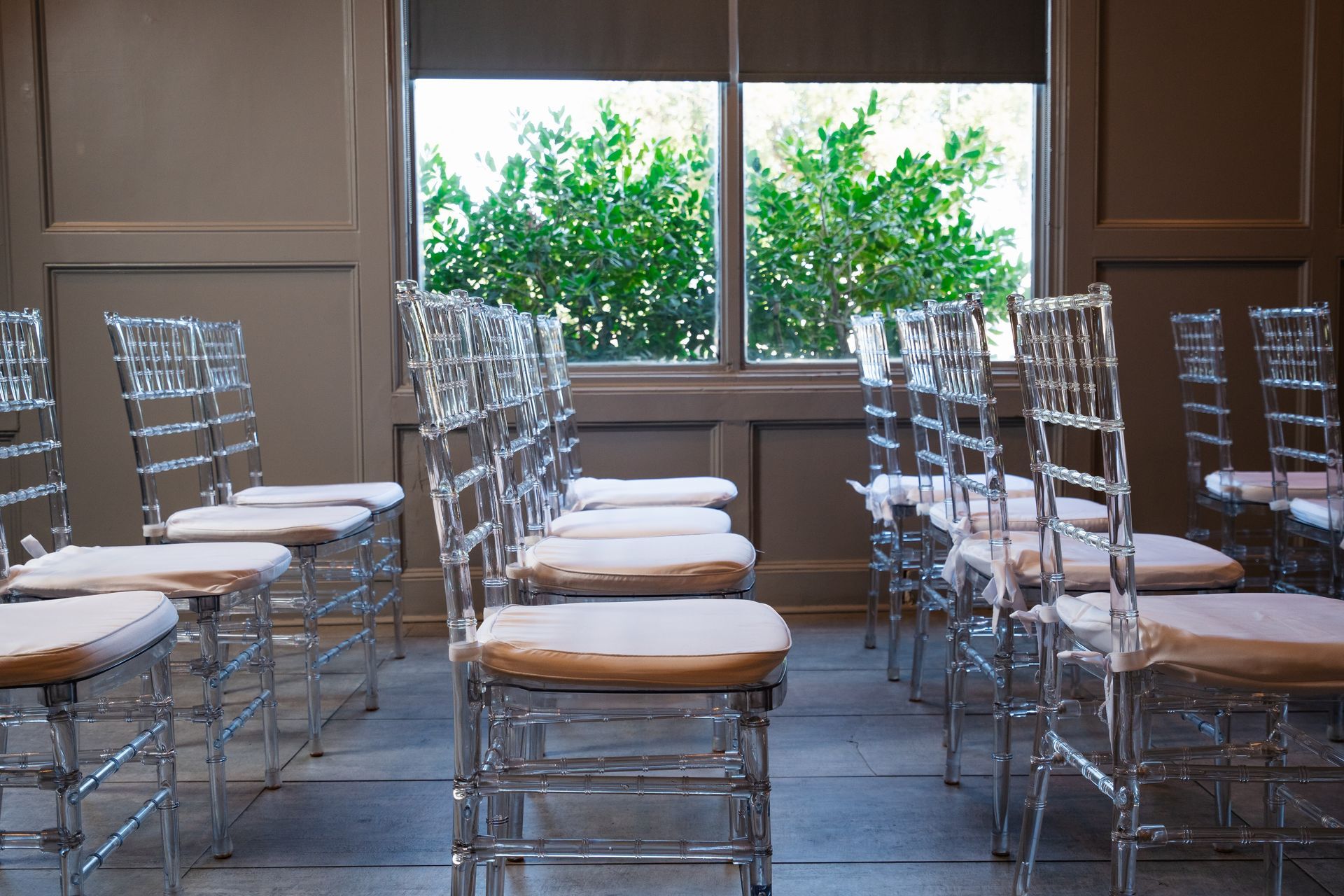 A row of clear chairs are lined up in front of a window.