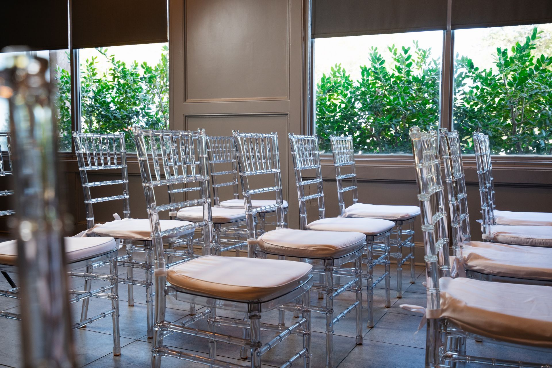 A row of clear chairs are lined up in front of a window.