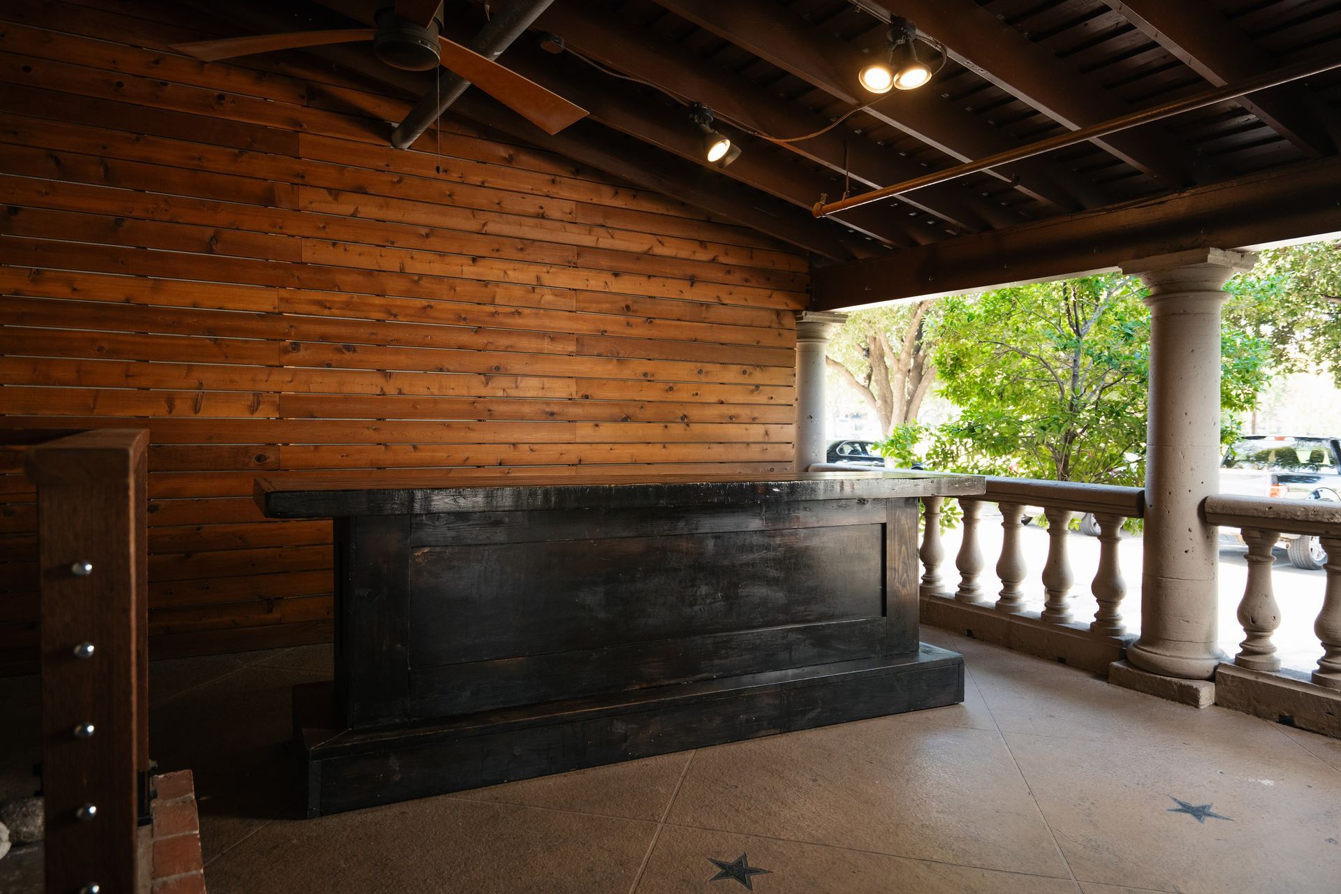 An empty porch with a wooden wall and a black table.