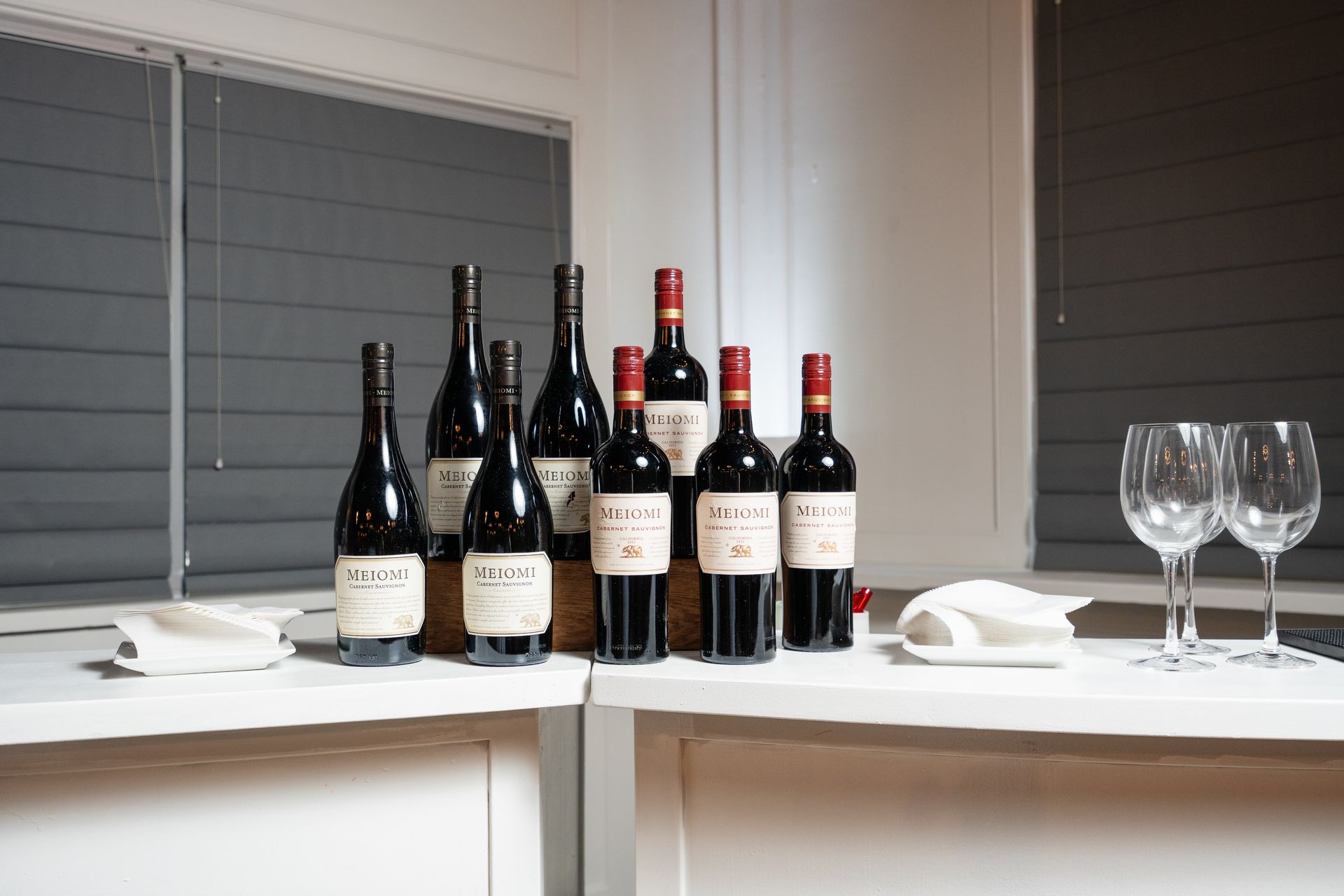 A table with bottles of wine and wine glasses on it.