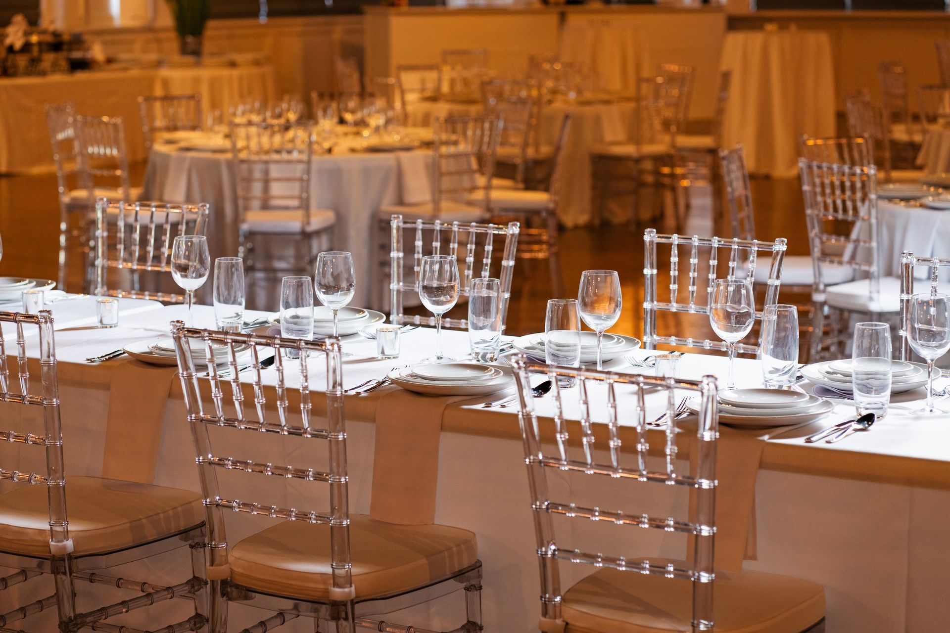 A dining room with tables and chairs set up for a wedding reception.
