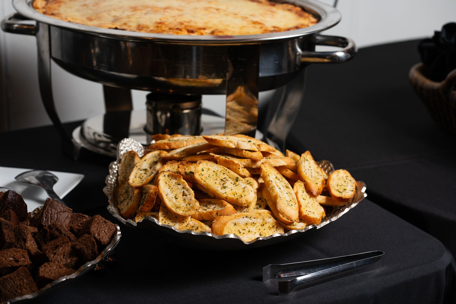 A buffet table with a pan of food and a plate of crackers.