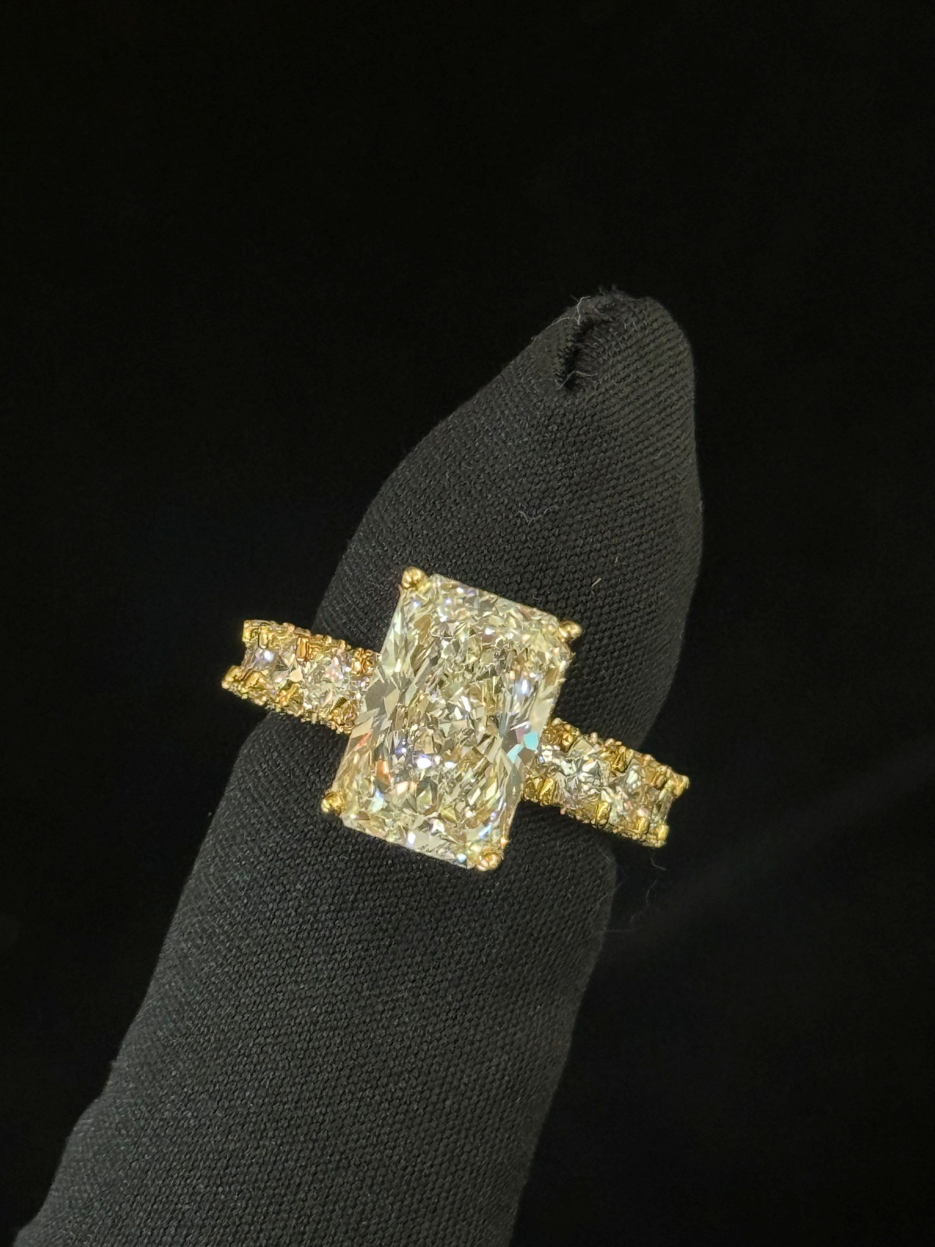 Gold diamond ring with a large rectangular center stone on a black velvet display stand