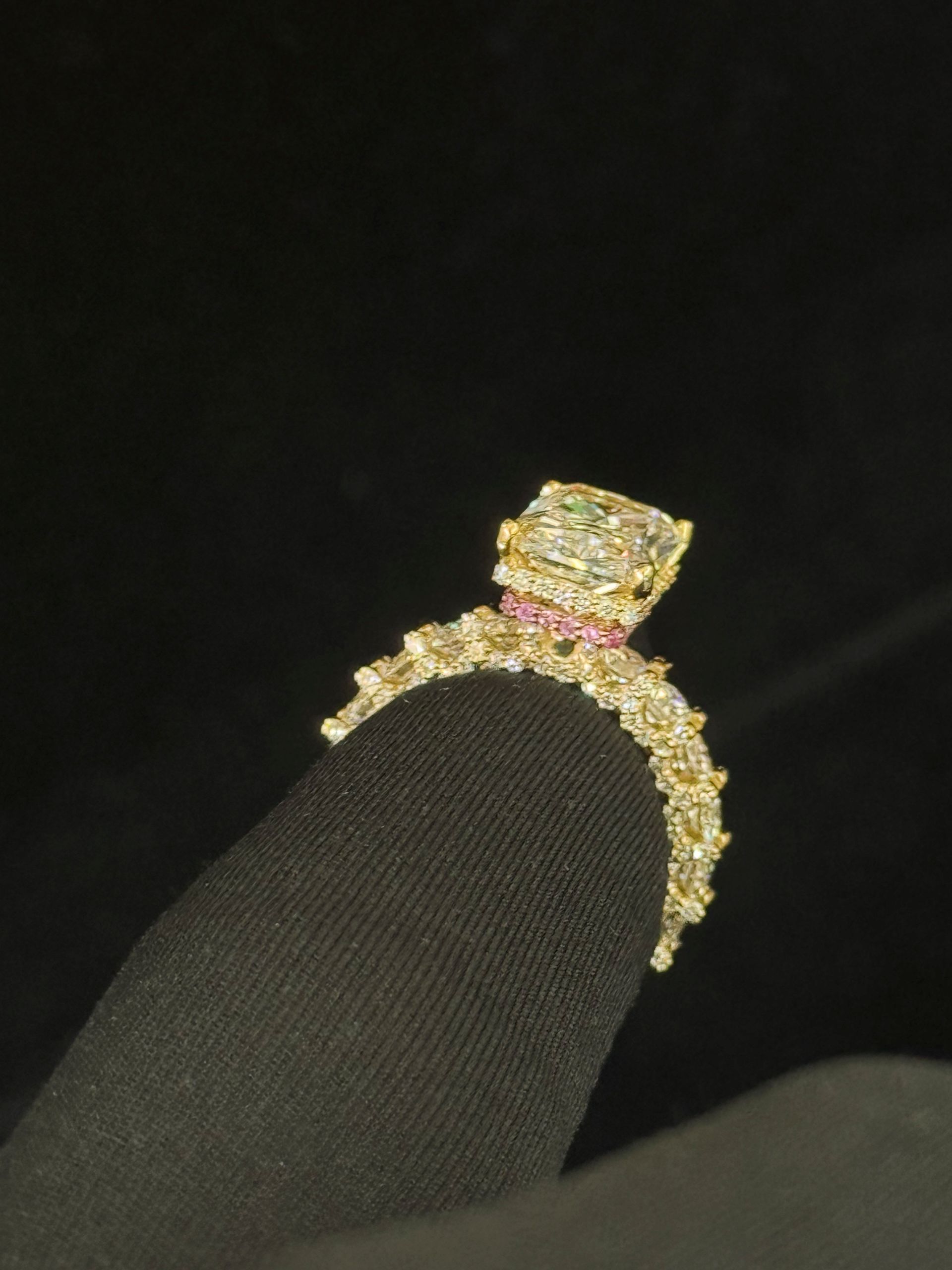 Diamond ring on a black fabric background, featuring a square-cut center stone and gold band