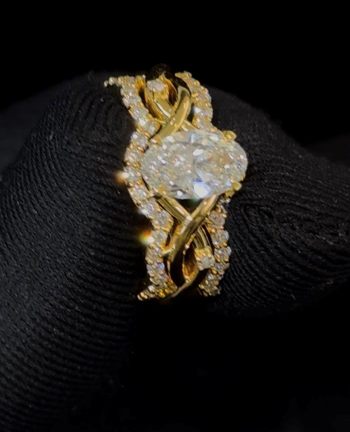 Gold ring with a large oval diamond, set on a black textured display