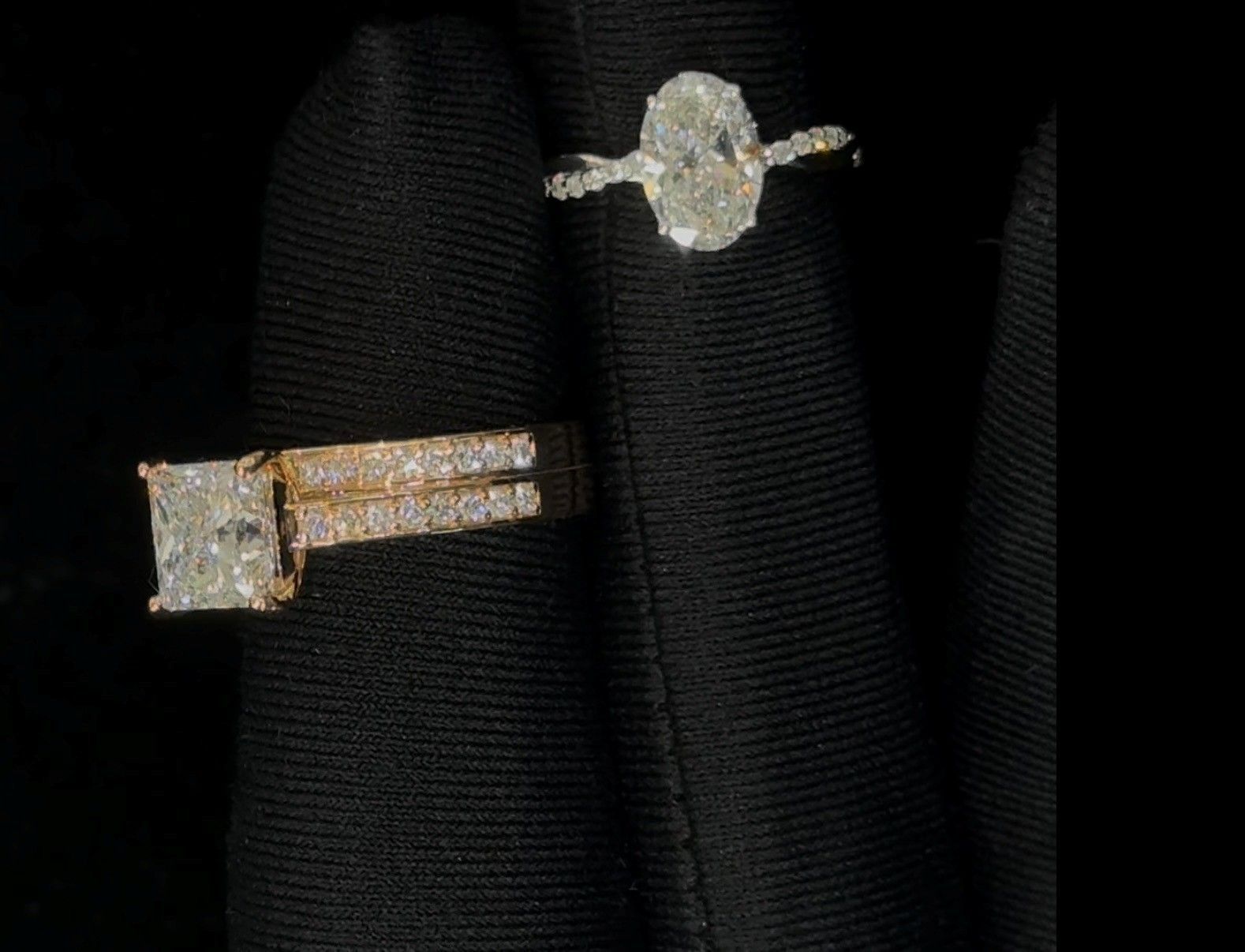 Two diamond rings on black fabric, one square-cut and one round-cut.
