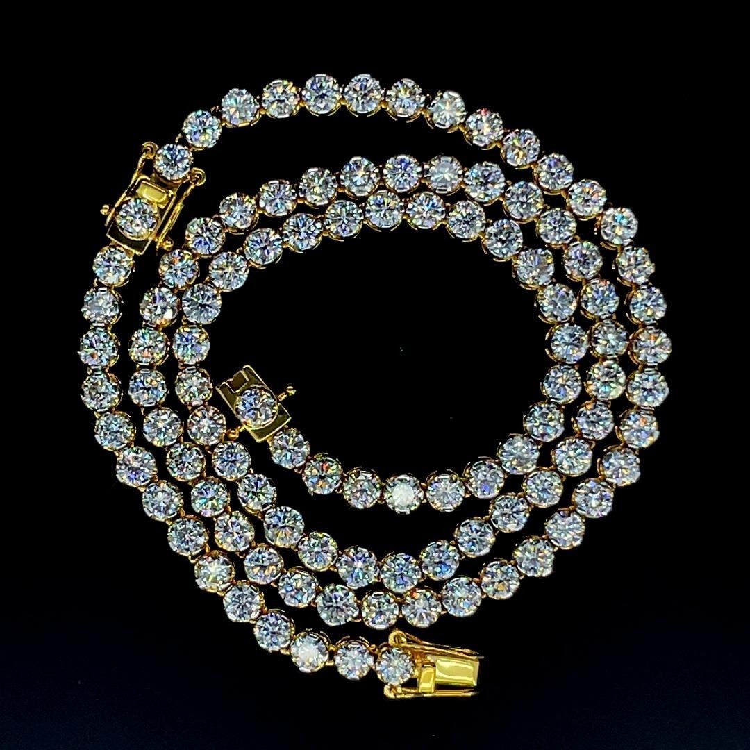 Coiled diamond tennis necklace with gold clasp on a black background