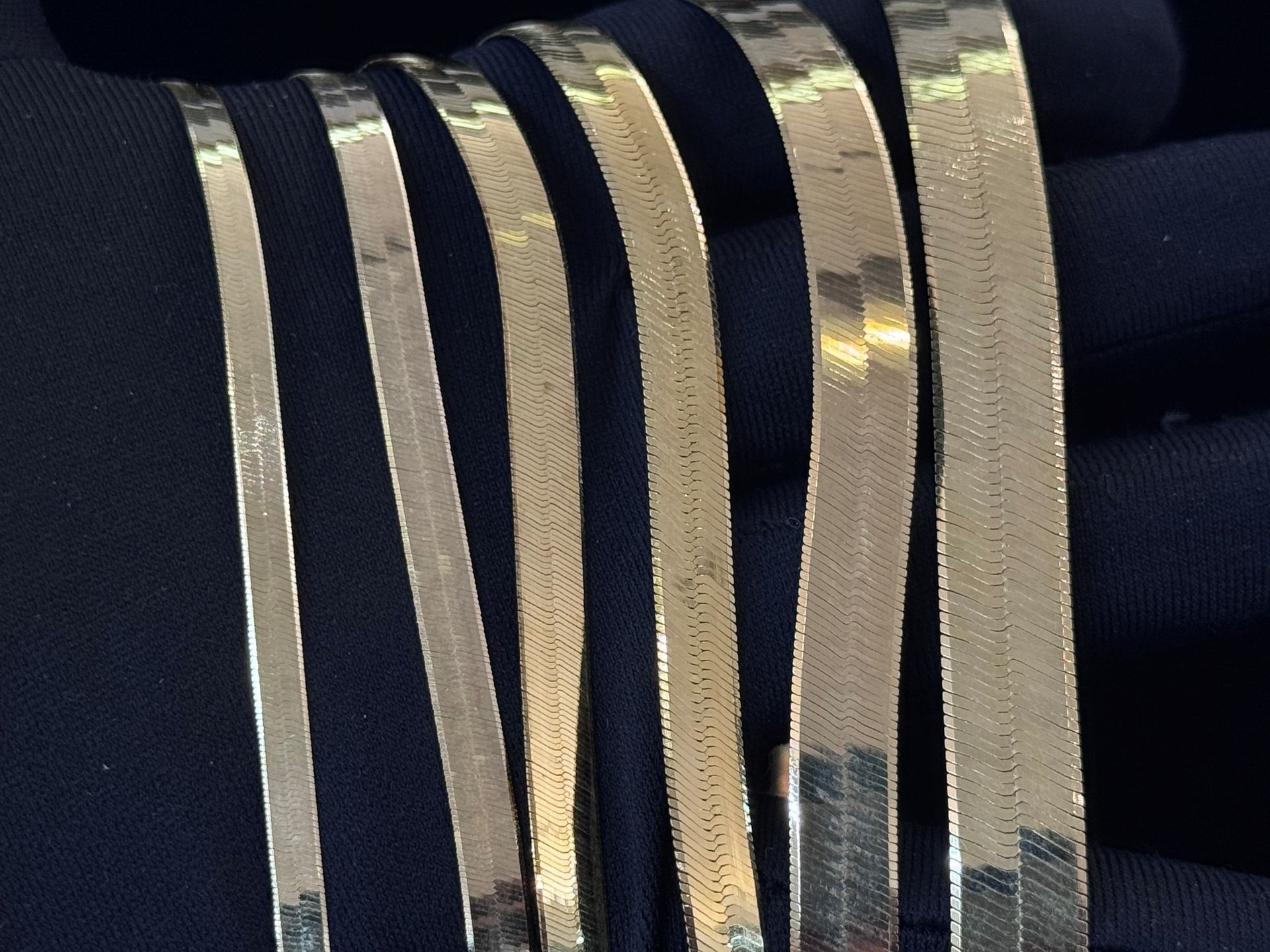 Close-up of shiny gold metallic strips against a dark fabric background
