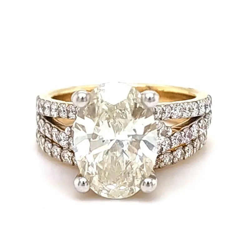 Gold ring with a large oval diamond and smaller side diamonds on a white background