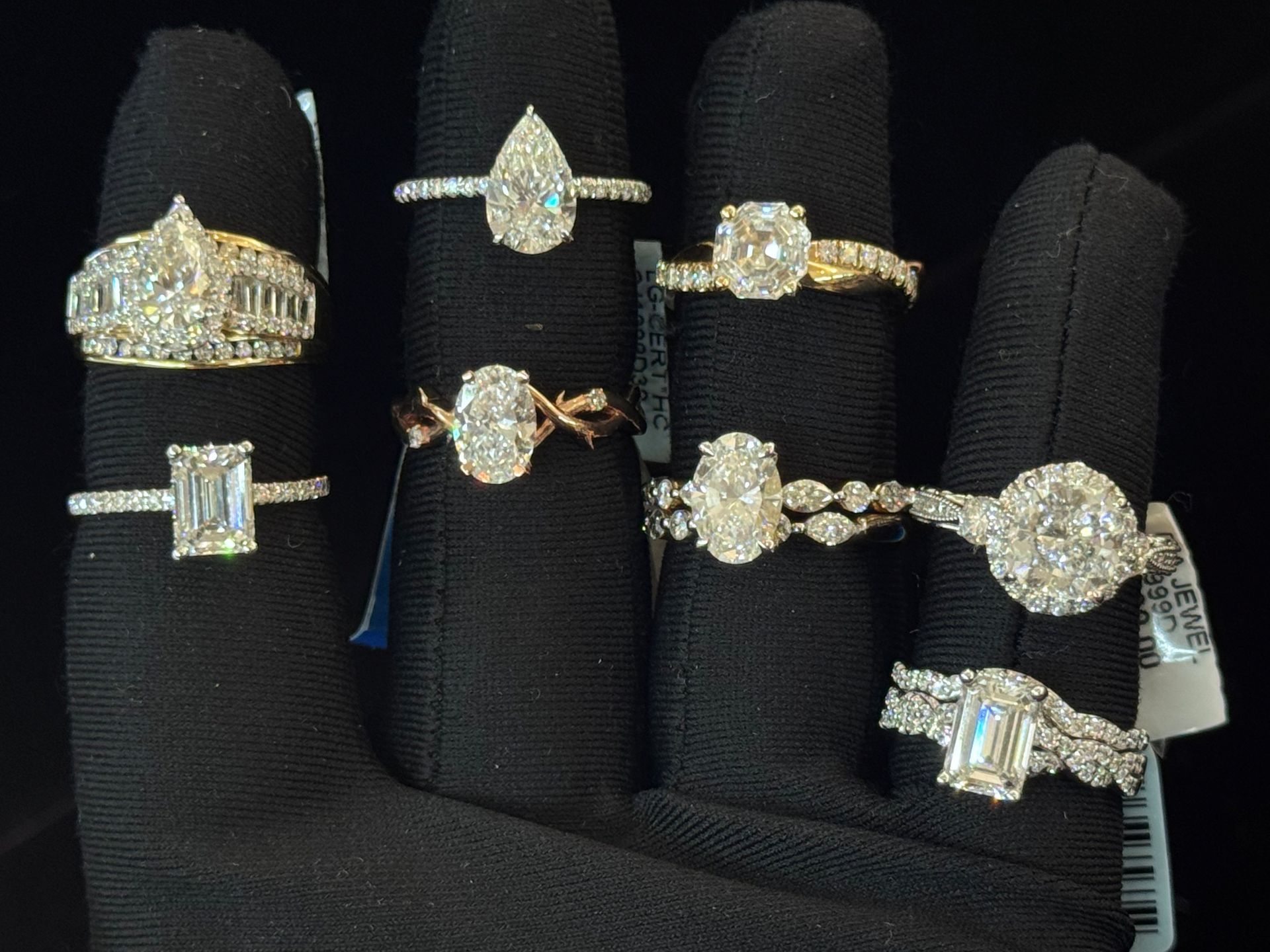 Assortment of diamond rings displayed on black ring holders.