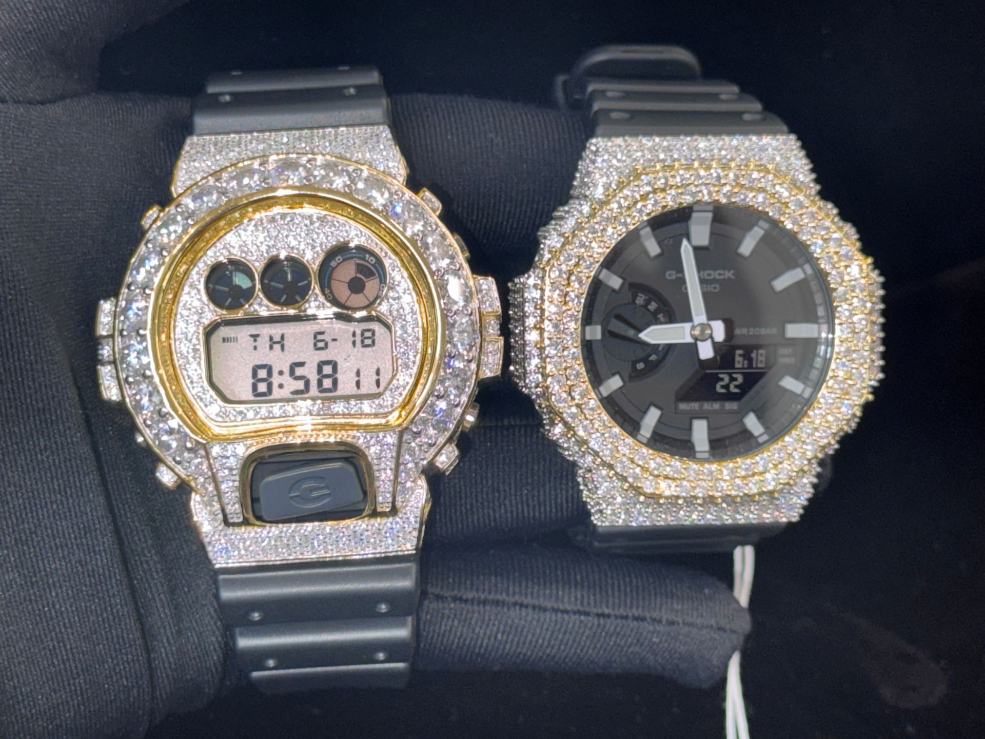 Two diamond-studded wristwatches on a black surface, one digital and one analog, both silver-toned.